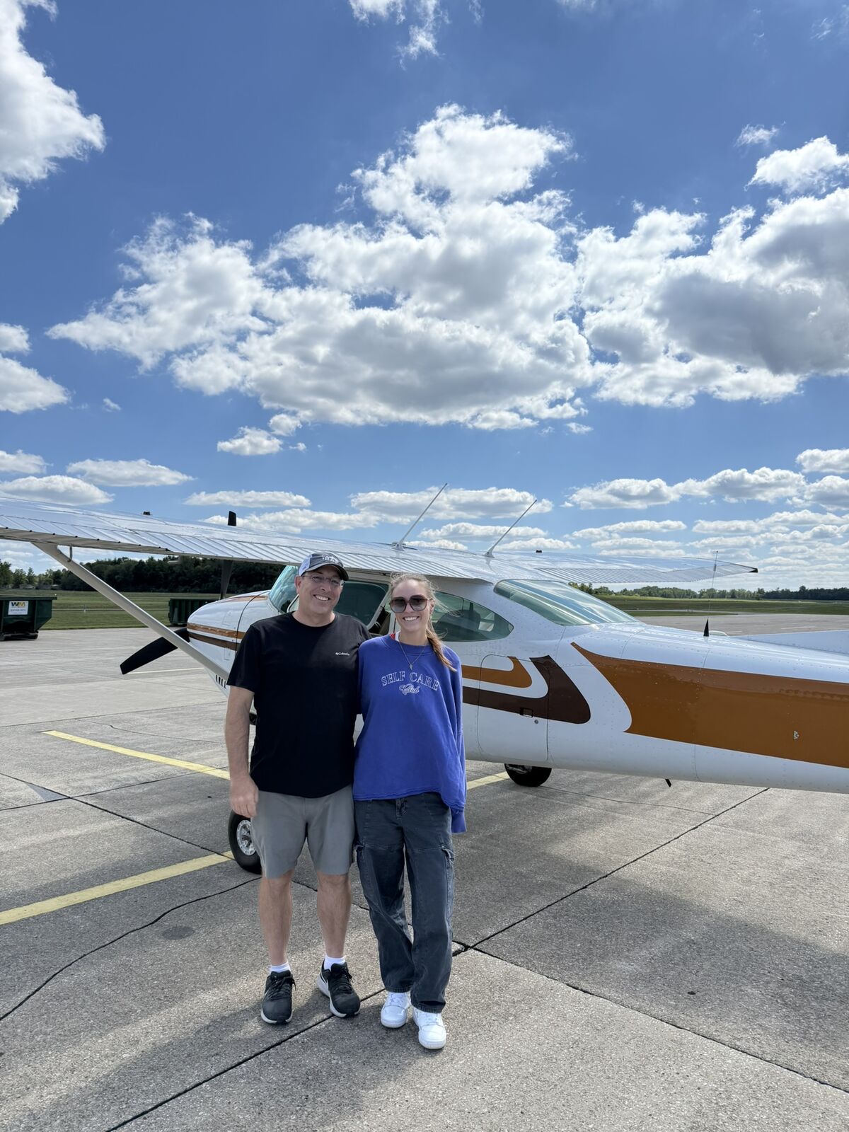 Two club members standing in front of a Cessna on the ramp.
