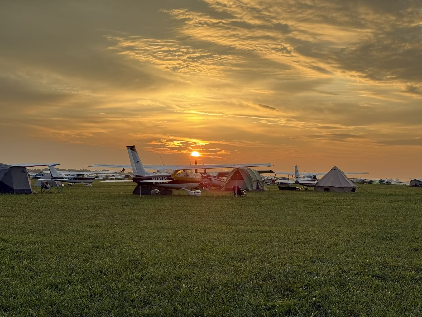 Aircraft and tents at sunset during a fly-in campout.
